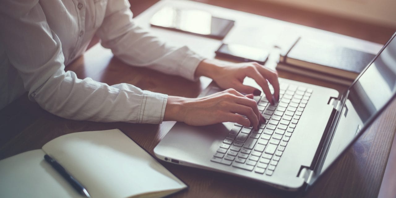 Woman working in home office hand on keyboard close up.
