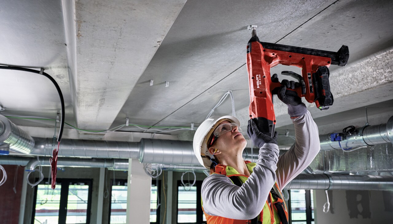 a worker checks a battery-powered direct fastener with a smart phone
