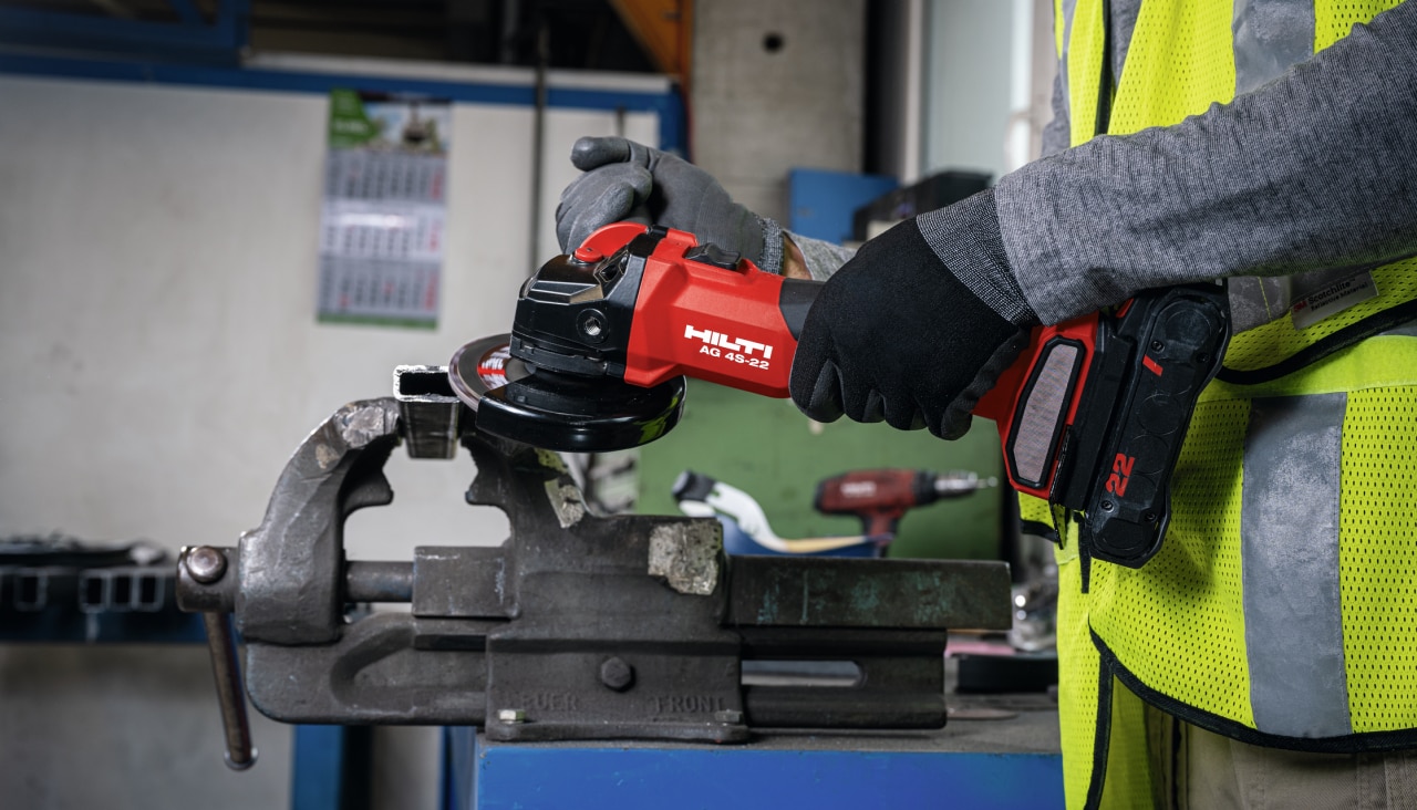 Worker grinding metal on a workbench with the cordless angle grinder AG 4S-22.