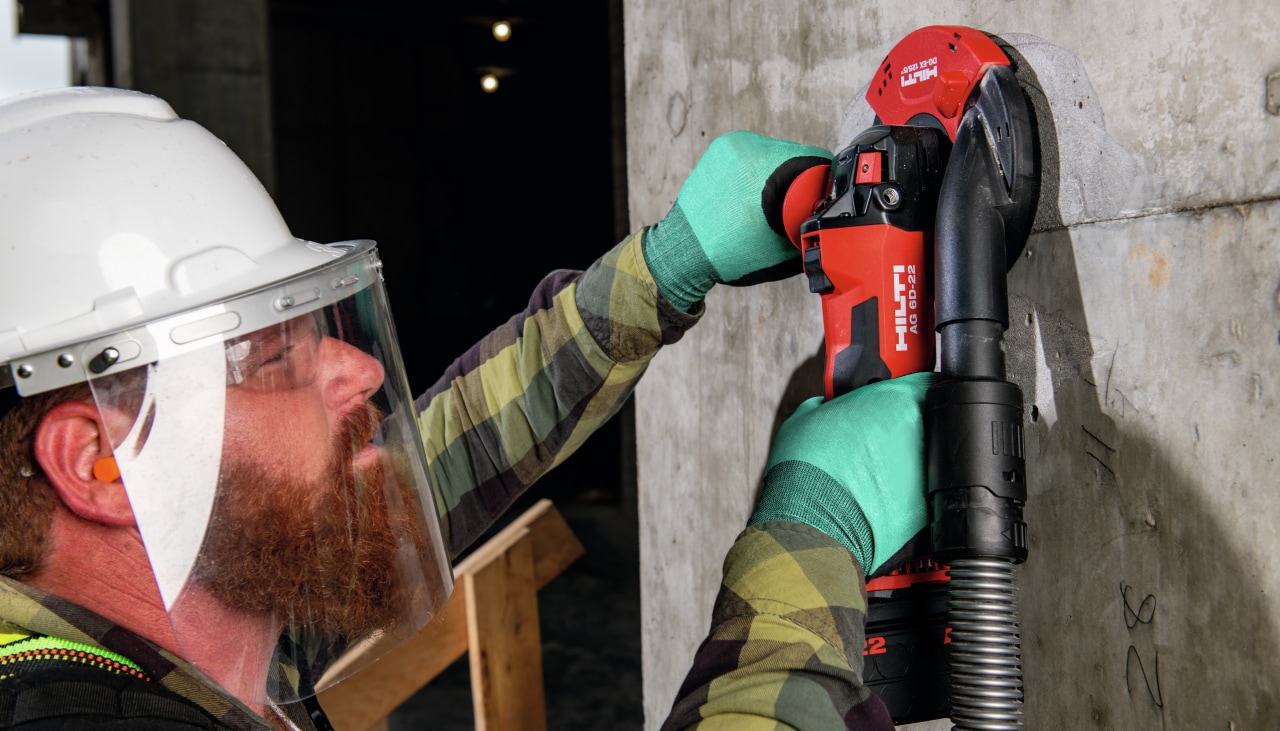 Worker cutting concrete with AG 6D-22 angle grinder connected to a vacuum (DRS)